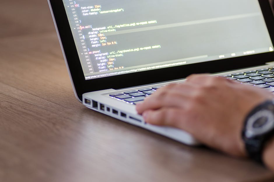 Image showing a close-up view of a laptop on a wooden surface, with visible lines of code displayed on the screen. Next to the laptop, there is a ceramic coffee mug with a beige background and black a